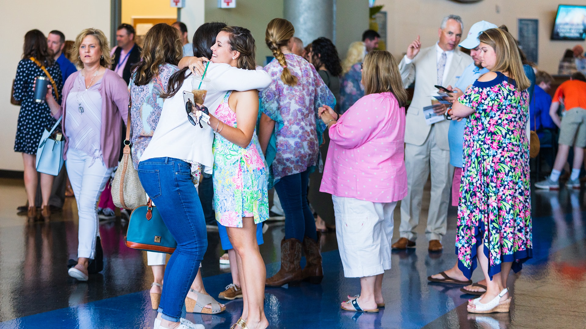 People in all forms of apparel gathering outside of the Brookwood Church auditorium to talk.